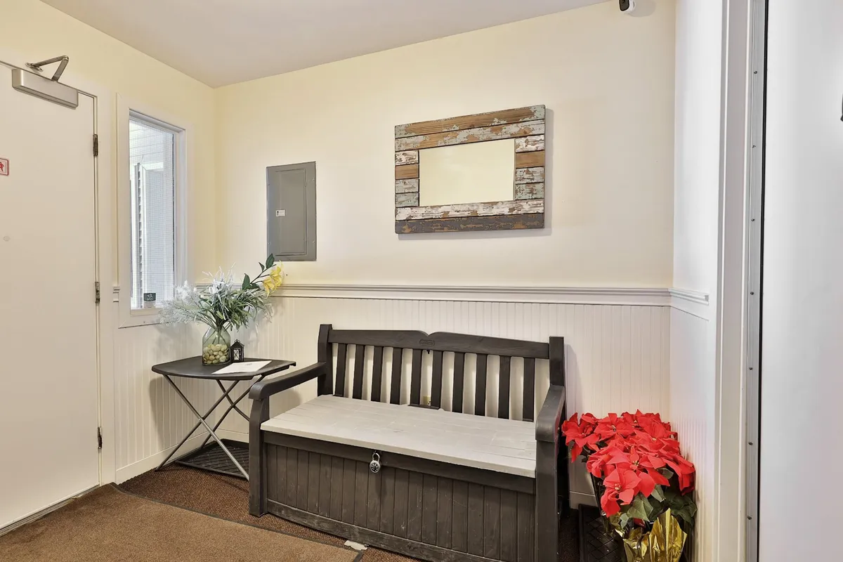 A welcoming entryway with a wooden bench, mirror, and pops of red from potted flowers invites guests into the property. The setup hints at the transition from outdoor adventures back into a comfortable home base, with space to sit, take off shoes, and drop belongings after a day outdoors.