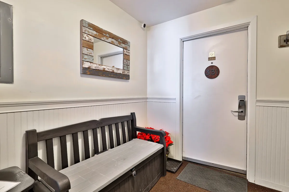 The entry area of the property, featuring a wooden bench, a mirror, and a doorway. The setting is functional yet welcoming, designed for guests to pause, organize, and prepare for a day outside.